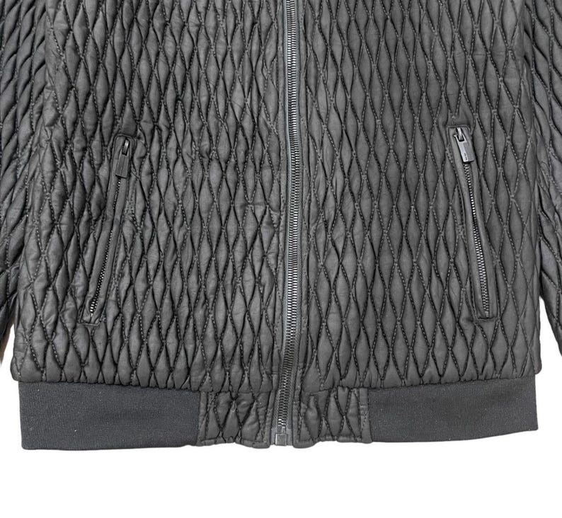 Puede incluir: Chaqueta negra acolchada con un patr&oacute;n de diamantes. Cuenta con cremallera completa, dos bolsillos con cremallera y dobladillo y pu&ntilde;os de canal&eacute;. La chaqueta est&aacute; hecha de un material texturizado.