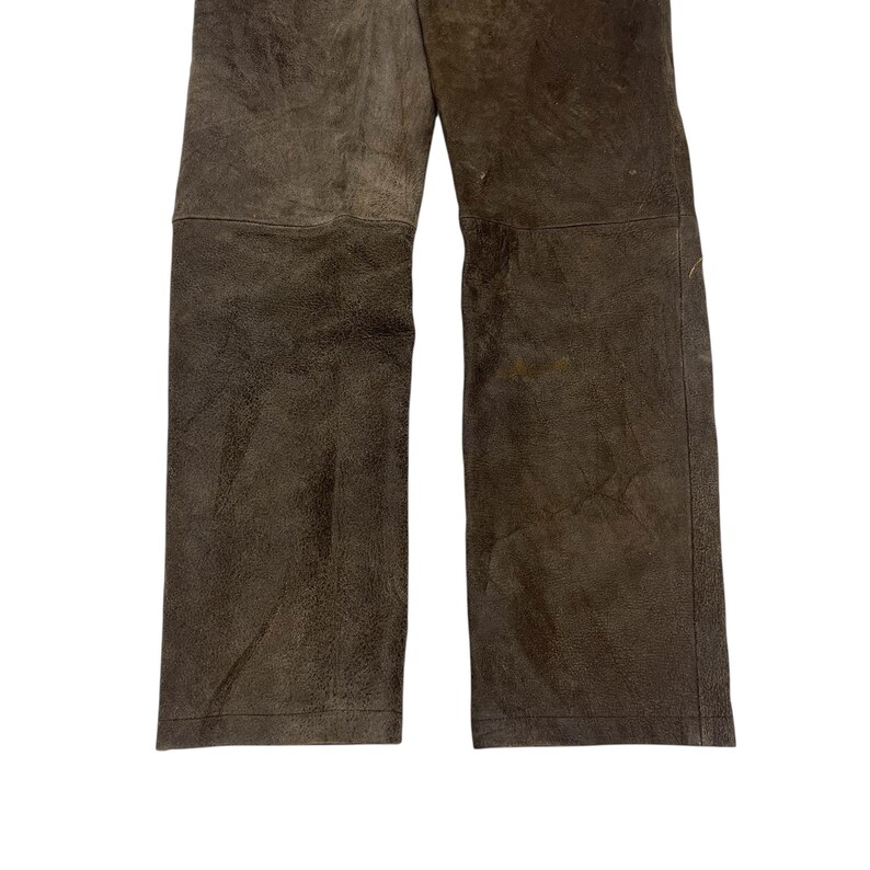 Pode incluir: Cal&ccedil;as de couro castanho com design de perna reta. As cal&ccedil;as t&ecirc;m uma apar&ecirc;ncia texturizada e uma paleta de cores neutras. A imagem mostra a parte inferior das cal&ccedil;as, destacando os detalhes do material e das costuras. Adequado para v&aacute;rias ocasi&otilde;es.