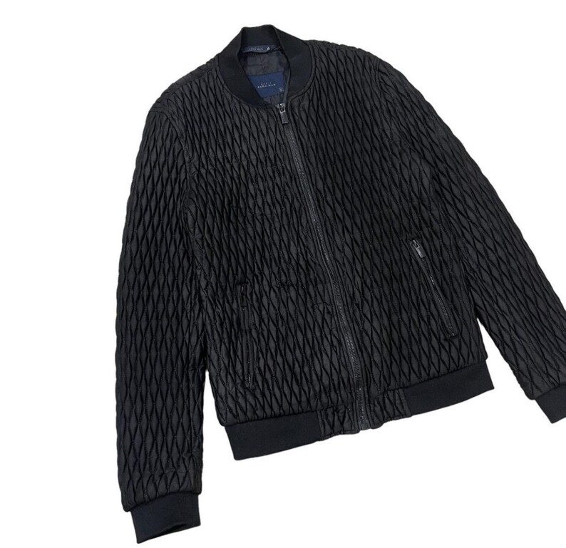 Puede incluir: Chaqueta bomber acolchada negra con cierre de cremallera completo, dos bolsillos delanteros y pu&ntilde;os y dobladillo de canal&eacute;. La chaqueta tiene un patr&oacute;n de diamantes texturizado y un cuello bomber cl&aacute;sico.