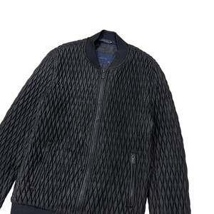Puede incluir: Chaqueta bomber acolchada negra con un patr&oacute;n de diamantes. La chaqueta tiene una cremallera frontal, dos bolsillos laterales y un cuello y pu&ntilde;os de canal&eacute;. La chaqueta est&aacute; hecha de un material texturizado y tiene un dise&ntilde;o minimalista.