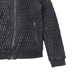 Puede incluir: Chaqueta bomber acolchada negra con un patr&oacute;n de diamantes. La chaqueta tiene cierre de cremallera completo, un bolsillo en el pecho con cremallera y pu&ntilde;os y dobladillo de canal&eacute;. La chaqueta es de material texturizado.