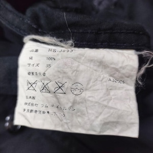 May include: Close-up of a white clothing tag with Japanese text and symbols, including "HS-J093", "100%", and "SS". The tag is attached to a dark fabric, with the code "AJ2005" visible.