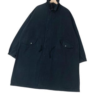 Puede incluir: Abrigo largo de color azul marino oscuro con cuello alto y dos bolsillos delanteros. El abrigo tiene una botonadura frontal y un cord&oacute;n en la cintura. El abrigo est&aacute; colgado de una percha de madera.