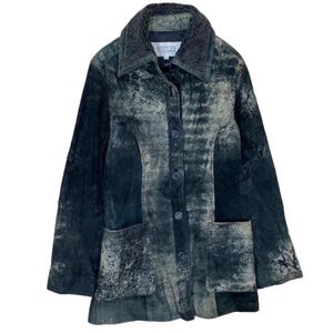 May include: A vintage, button-down jacket in shades of dark green and gray. The jacket features a textured, distressed appearance, a plush collar, and two front pockets. The jacket has a classic, tailored fit.