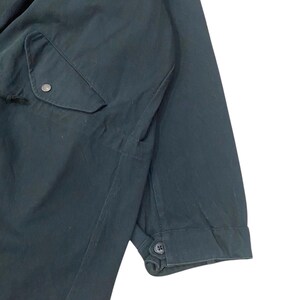 Puede incluir: Chaqueta verde oscuro con un bolsillo y pu&ntilde;os abotonados. La chaqueta tiene un dise&ntilde;o sencillo y funcional, centrado en la practicidad y una est&eacute;tica limpia. La tela parece ser un material duradero, adecuado para diversas condiciones clim&aacute;ticas.