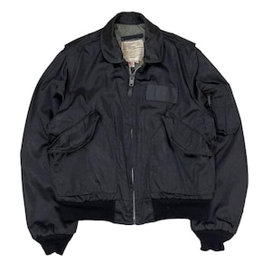 May include: Black bomber jacket with a zip-up front, two front pockets, and a patch on the chest. The jacket has a ribbed hem and cuffs. The collar is a classic style. The jacket is made of a smooth material, possibly nylon.