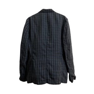 May include: A dark gray blazer with a plaid pattern. The jacket has long sleeves and a notched lapel. The back of the blazer is visible, showing the tailored fit and the fabric's texture. The color scheme is primarily dark gray and black.