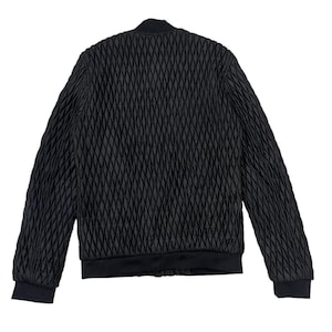 Puede incluir: Chaqueta bomber negra con un patr&oacute;n de diamantes acolchado. La chaqueta presenta cuello, pu&ntilde;os y dobladillo de canal&eacute;. La vista trasera de la chaqueta se muestra sobre un fondo blanco. La chaqueta es de color negro s&oacute;lido.