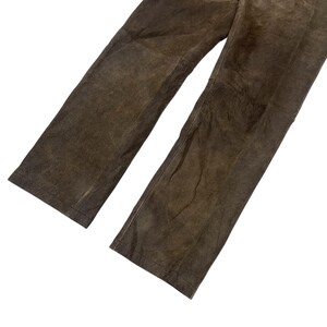 Pode incluir: Cal&ccedil;as de couro castanho com design de perna reta. As cal&ccedil;as t&ecirc;m um aspeto desgastado, com textura vis&iacute;vel e varia&ccedil;&otilde;es de cor. O couro parece macio e flex&iacute;vel.