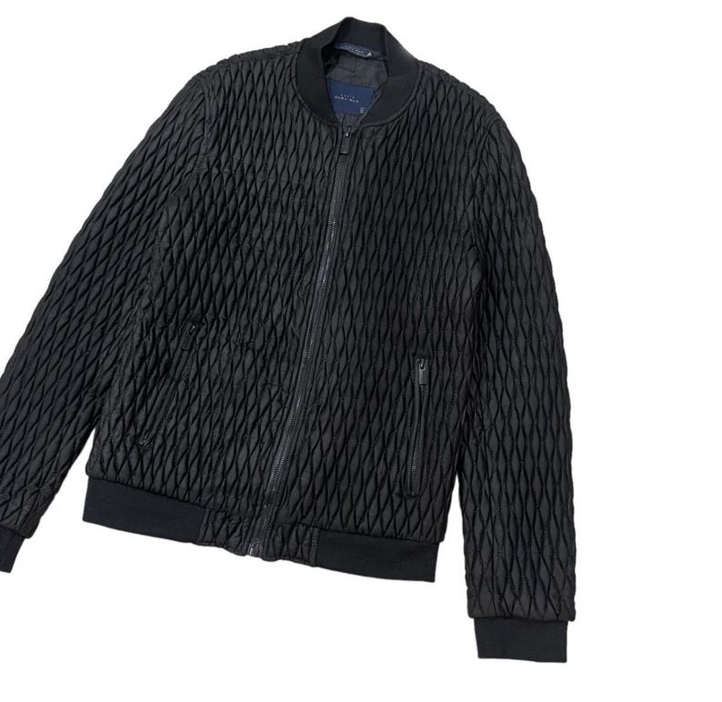 Puede incluir: Chaqueta bomber negra con un patr&oacute;n de diamantes acolchado. La chaqueta tiene una cremallera completa, dos bolsillos delanteros y pu&ntilde;os y dobladillo de canal&eacute;. La chaqueta es de color negro liso y tiene un estilo bomber cl&aacute;sico.