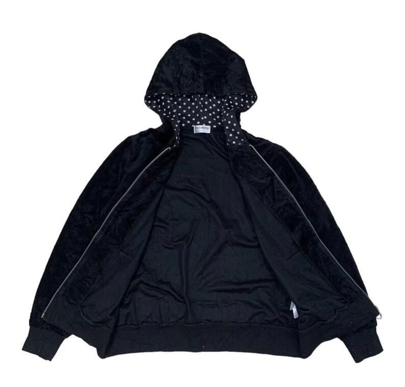 Puede incluir: Sudadera negra con cremallera y capucha con lunares blancos. La chaqueta est&aacute; abierta, revelando el forro interior. Los pu&ntilde;os y el dobladillo son de color negro liso. La sudadera con capucha est&aacute; hecha de un material suave y aterciopelado.