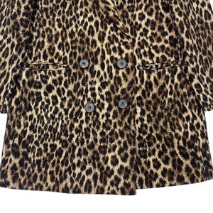 May include: A double-breasted leopard print blazer with four dark buttons and two front pockets. The jacket features a classic notched lapel and a brown, black, and tan spotted pattern.