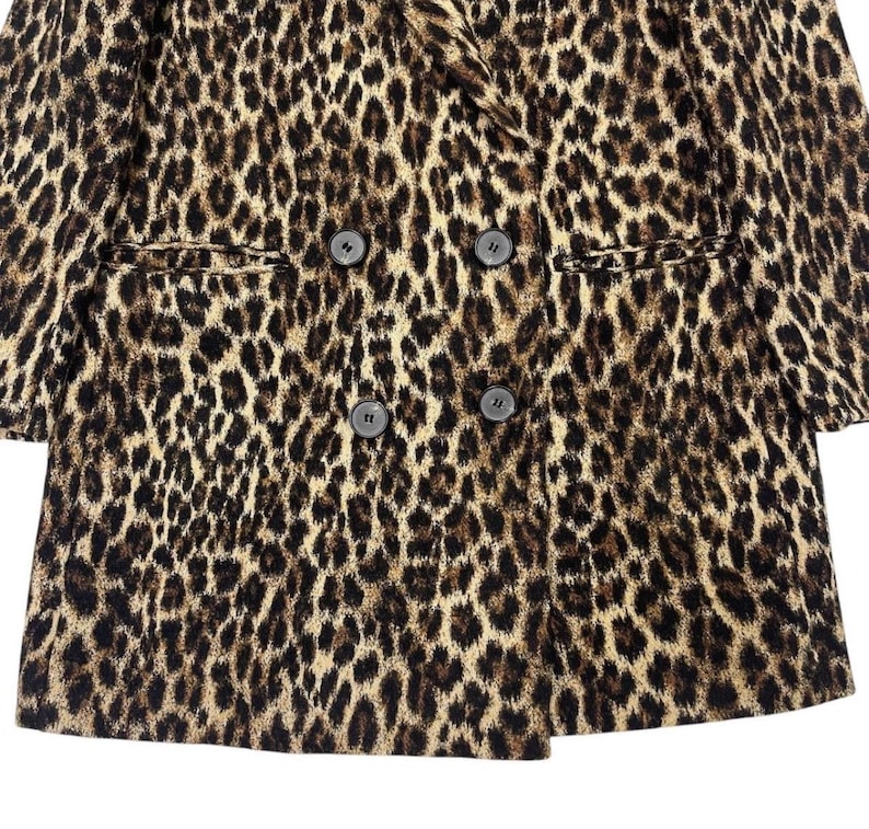 May include: A double-breasted leopard print blazer with four dark buttons and two front pockets. The jacket features a classic notched lapel and a brown, black, and tan spotted pattern.
