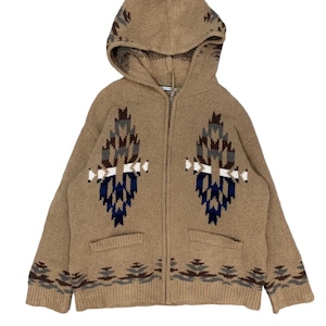 May include: A tan zip-up hooded sweater with a geometric pattern in shades of brown, blue, and white. The sweater has a hood and two front pockets. The pattern is repeated on the hood and the bottom hem.
