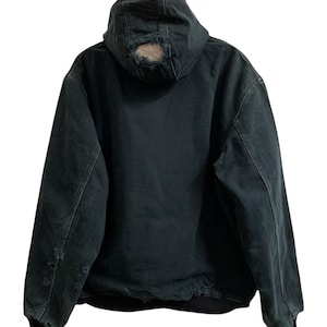 May include: Dark green hooded jacket with distressed details. The jacket features a hood with a hole, ribbed cuffs, and a black bottom hem. The jacket is made of a durable material.