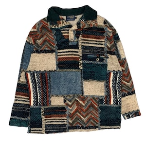 Könnte beinhalten: Ein langärmliger Patchwork-Pullover in Blau-, Beige- und Brauntönen. Der Pullover hat einen Kragen und eine Knopfleiste. Der Stoff ist ein strukturierter Strick, mit verschiedenen geometrischen Mustern.