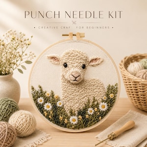 Op de afbeelding: Een punch needle set met een ronde houten borduurring met een textuurrijk crèmekleurig lammetjesontwerp omringd door groen gebladerte en witte madeliefjes. De tekst PUNCH NEEDLE KIT CREATIVE CRAF FOR BEGINNERS staat erboven gedrukt.
