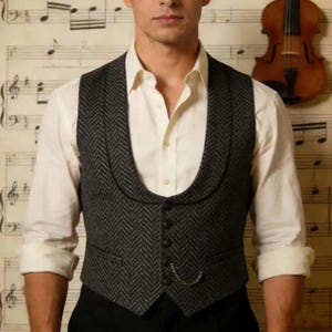 May include: A grey herringbone waistcoat with a shawl collar and a four-button fastening. The waistcoat features small pockets and a watch chain. It is worn over a white dress shirt.