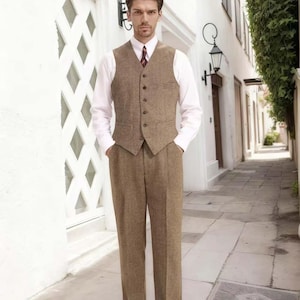May include: A three-piece brown tweed suit, including a vest, trousers, and a white dress shirt. The vest has a button-up front. The suit is paired with a patterned tie and brown leather shoes. The outfit is classic and tailored.