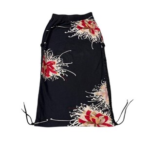 May include: Black skirt with a floral pattern featuring red, white, and tan flowers. The skirt has a drawstring waist and a flowing design. The floral print is a prominent design element, adding a touch of elegance to the garment.