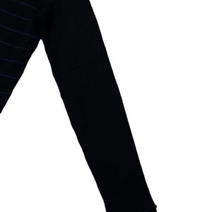 Puede incluir: Top negro de manga larga con sutiles rayas moradas. Se ve la manga, con un pu&ntilde;o acanalado. La tela parece ser un punto suave, adecuado para usar solo o en capas. El dise&ntilde;o es sencillo y vers&aacute;til.