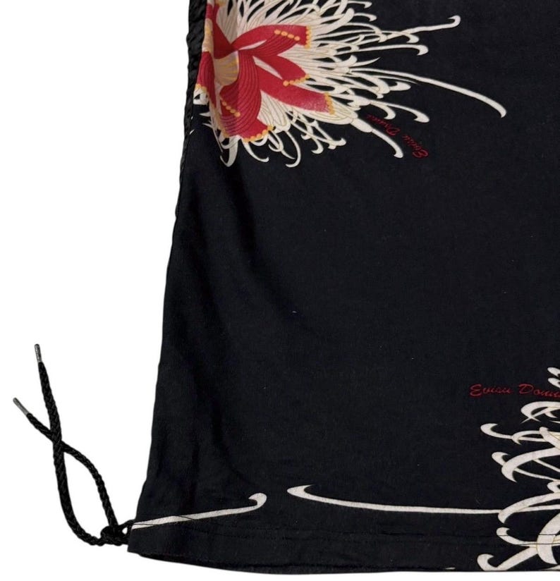 May include: Black garment with a floral design in red, cream, and white. The design features a large flower and flowing lines. The garment has a drawstring and the text "Evisu Dou" in red.