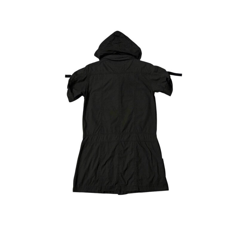 Puede incluir: Chaqueta negra con capucha y mangas cortas. La chaqueta tiene cintura con cord&oacute;n y cierre de botones. La capucha est&aacute; adjunta y la chaqueta tiene un dise&ntilde;o simple y utilitario. La chaqueta est&aacute; hecha de tela ligera.