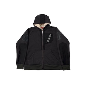 May include: Dark grey zip-up hoodie with a hood and a cream-coloured lining. The jacket features black patches on the sleeves and chest, with text and military-style insignia. The hoodie has a full-length zip and ribbed hem and cuffs.