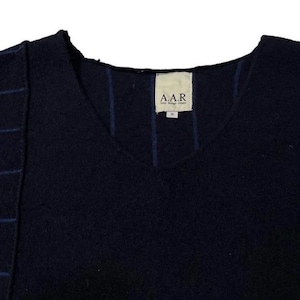 Puede incluir: Un su&eacute;ter azul marino con cuello en V con un dise&ntilde;o &uacute;nico. El hombro izquierdo presenta costuras azules horizontales, y l&iacute;neas azules verticales acent&uacute;an el frente. La etiqueta dice "A.A.R." en texto blanco.