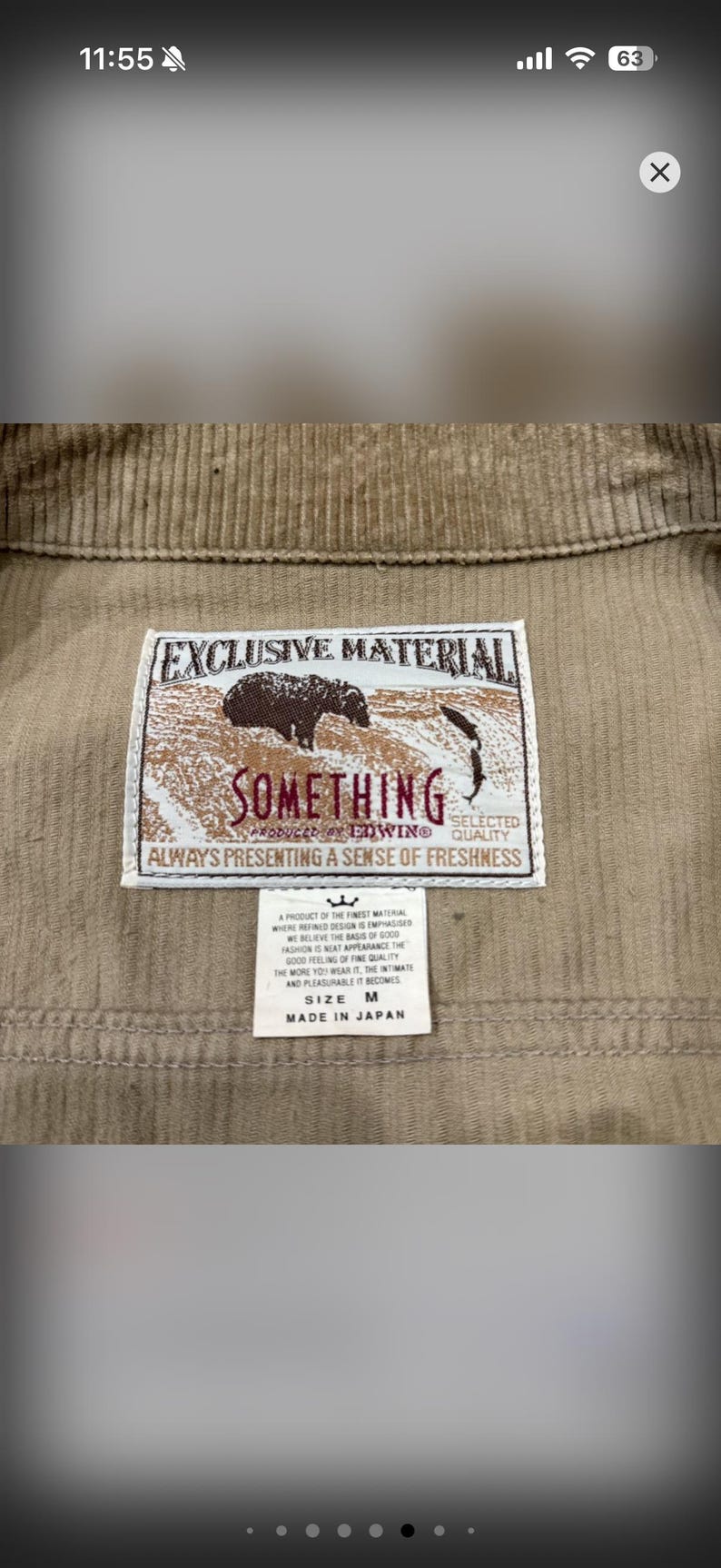 K&ouml;nnte beinhalten: Nahaufnahme einer beigefarbenen Cordjacke mit einem Etikett mit der Aufschrift "EXCLUSIVE MATERIAL SOMETHING". Das Etikett enth&auml;lt auch den Text "ALWAYS PRESENTING A SENSE OF FRESHNESS". Die Jacke ist Gr&ouml;&szlig;e M und hergestellt in Japan.