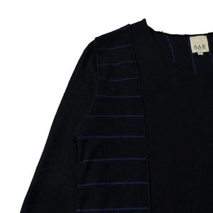 Puede incluir: Camiseta negra de manga larga con cuello redondo y un dise&ntilde;o &uacute;nico. La camiseta presenta rayas horizontales azul oscuro en la manga izquierda y un panel vertical. La etiqueta en la parte posterior del cuello dice "AAR".