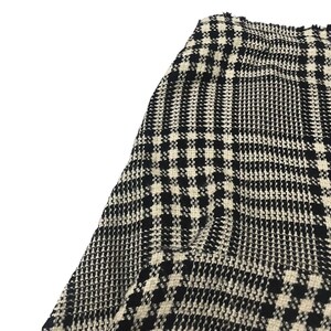 May include: Close-up of a black and white houndstooth pattern fabric. The fabric has a woven texture with a repeating pattern of small squares and vertical lines. The color scheme is a classic combination of black and off-white.