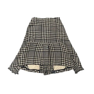 May include: A black, white, and gray plaid skirt. The skirt has a unique design with a pleated front and a flared shape. The fabric appears to be a woven material, and the hemline has a frayed edge. The skirt is displayed against a white background.