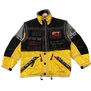 以下が含まれることがあります： 黒と黄色のヴィンテージFila Adventureジャケット。 ジャケットには複数のポケット、Filaのロゴ、および「Adventure」と「Bella Italia」のテキストがあります。 ジャケットはハイカラーとドローストリングウエストを備えています。