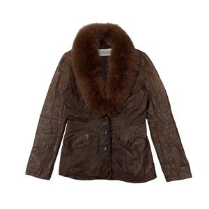 May include: A brown leather jacket with a fur collar. The jacket has a button-up front, two front pockets, and a textured appearance. The fur collar is a darker shade of brown, creating a contrast with the jacket's color.