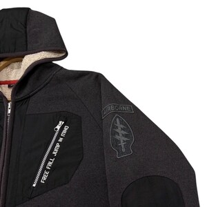 May include: Dark grey hooded jacket with a black chest panel and a black sleeve patch. The jacket features a zip closure and the text "FREE FALL JUMP IN MIND" is printed on the chest panel.