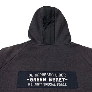 May include: Dark grey hoodie with a black hood lining. The back features a patch with the text "DE OPPRESSO LIBER - GREEN BERET - U.S. ARMY SPECIAL FORCE." Patches are visible on the sleeves. A casual, military-inspired garment.