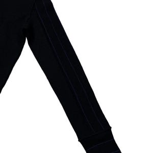 Puede incluir: Manga de camisa negra de manga larga con tres rayas verticales azul marino en el brazo. El pu&ntilde;o tambi&eacute;n tiene rayas azul marino. La camisa est&aacute; hecha de un material suave y c&oacute;modo.