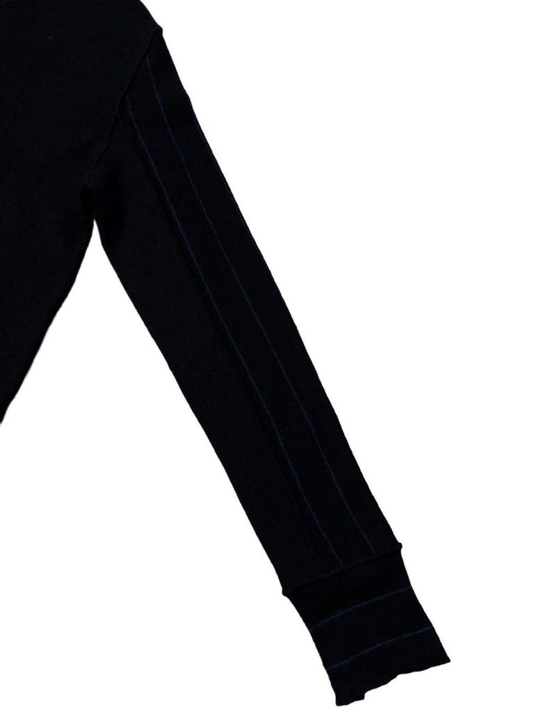 Puede incluir: Manga de camisa negra de manga larga con tres rayas verticales azul marino en el brazo. El pu&ntilde;o tambi&eacute;n tiene rayas azul marino. La camisa est&aacute; hecha de un material suave y c&oacute;modo.