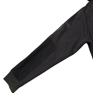 May include: Dark grey hoodie sleeve with a black elbow patch and a patch that says "AIRBORNE". The sleeve has a ribbed cuff and a black patch on the elbow.