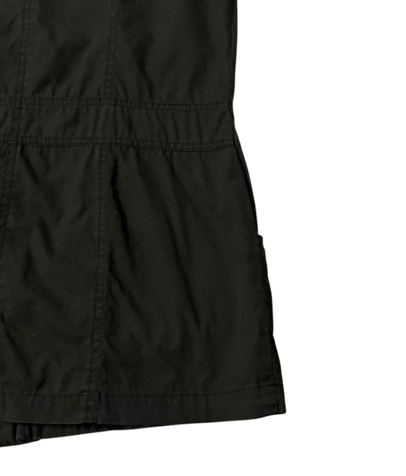 Puede incluir: Prenda negra con costuras visibles y un dise&ntilde;o estructurado. La tela parece ser un material resistente, con costuras horizontales que crean una zona de cintura definida. La prenda tiene un bolsillo lateral.