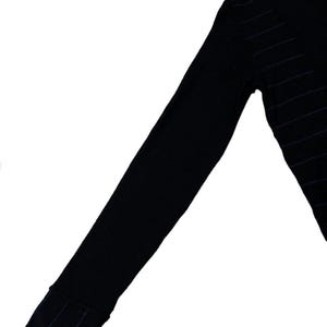 Puede incluir: Su&eacute;ter negro de manga larga con finas rayas horizontales azul marino. El su&eacute;ter tiene un detalle de pu&ntilde;o acanalado en la mu&ntilde;eca. El su&eacute;ter con cuello en V est&aacute; hecho de un material de punto suave.