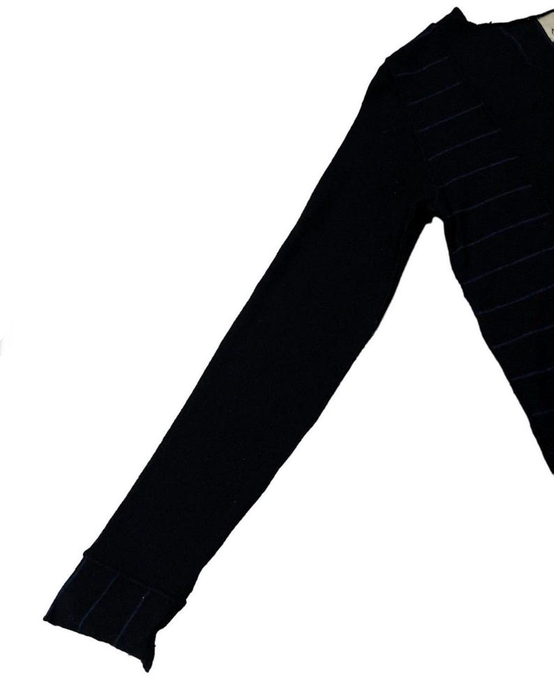 Puede incluir: Su&eacute;ter negro de manga larga con finas rayas horizontales azul marino. El su&eacute;ter tiene un detalle de pu&ntilde;o acanalado en la mu&ntilde;eca. El su&eacute;ter con cuello en V est&aacute; hecho de un material de punto suave.