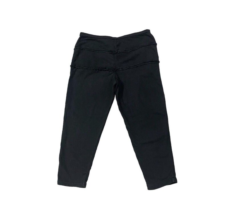 Puede incluir: Pantalones cortos negros con un dise&ntilde;o &uacute;nico en capas en la cintura. Los pantalones est&aacute;n hechos de un material suave y tienen un ajuste relajado. El largo corto termina justo debajo de la pantorrilla. Los pantalones son de color negro liso.