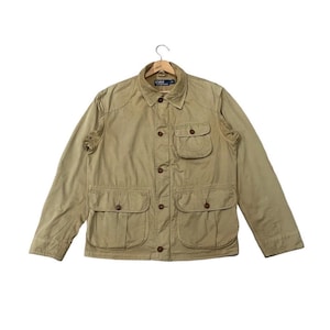 Puede incluir: Chaqueta de color beige con cuatro bolsillos delanteros y dos bolsillos en el pecho. La chaqueta tiene una botonadura frontal y un cuello. Fabricada con tejido resistente, es adecuada para actividades al aire libre.