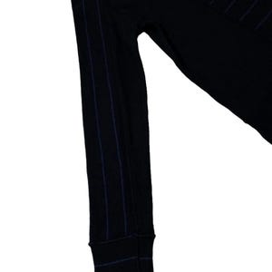 Puede incluir: Camisa negra de manga larga con finas rayas verticales azul marino. El pu&ntilde;o de la manga es visible, tambi&eacute;n con rayas azul marino. La camisa est&aacute; hecha de un material suave y c&oacute;modo.