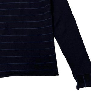 Puede incluir: Su&eacute;ter azul marino con rayas azules horizontales en el pecho y en los pu&ntilde;os. La manga larga se extiende hacia la derecha, mostrando el detalle del pu&ntilde;o acanalado. El su&eacute;ter tiene un dise&ntilde;o simple y cl&aacute;sico.