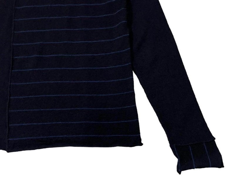 Puede incluir: Su&eacute;ter azul marino con rayas azules horizontales en el pecho y en los pu&ntilde;os. La manga larga se extiende hacia la derecha, mostrando el detalle del pu&ntilde;o acanalado. El su&eacute;ter tiene un dise&ntilde;o simple y cl&aacute;sico.