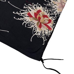 May include: Black fabric with a floral design featuring red, white, and gold chrysanthemum flowers. The fabric has a drawstring at the bottom. The flowers have intricate details and are set against a dark background.