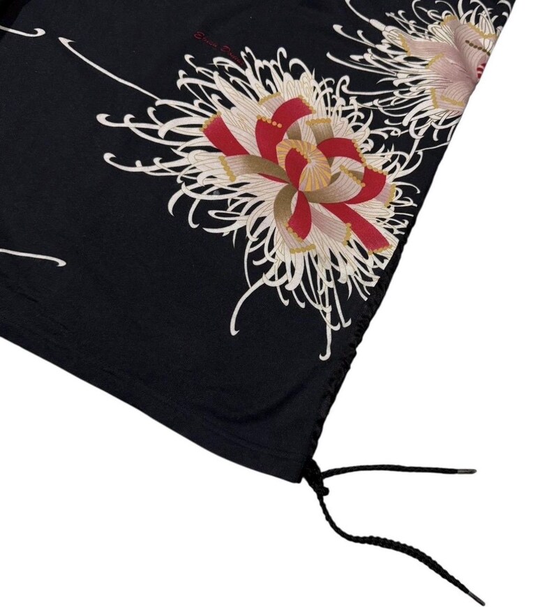 May include: Black fabric with a floral design featuring red, white, and gold chrysanthemum flowers. The fabric has a drawstring at the bottom. The flowers have intricate details and are set against a dark background.